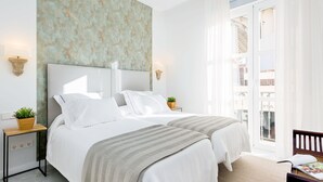 Hotelkamer met een groot bed, twee nachtkastjes met lampen, en uitzicht op het balkon, plus een wand met structuur.
