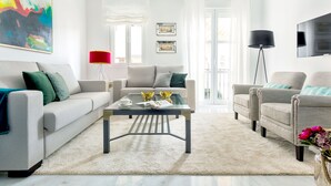 Een moderne woonkamer met een bank, fauteuils, een salontafel en een televisie.