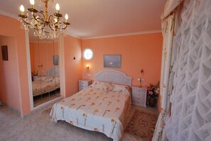 A bedroom with a bed, a nightstand, a dresser, a mirror, and a chandelier.
