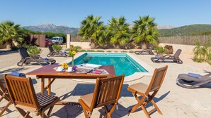 Un espace aménagé au bord de la piscine, avec des chaises longues, une table avec des magazines et une vue sur les montagnes.