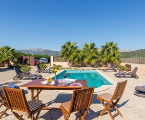 A poolside area with lounge chairs, a table with magazines, and a view of mountains. - Can Melis - Modern villa with pool near Campanet (Campanet)