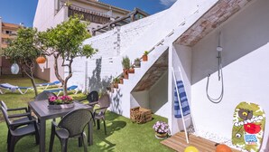 Un patio con una mesa, sillas, un árbol pequeño y una zona de juegos con un tobogán.