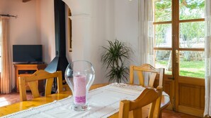 A dining area with a wooden table, chairs, a vase with pink beads, and a television in the background. - Banyols - Beautiful villa with pool in Alaró (Alaro)
