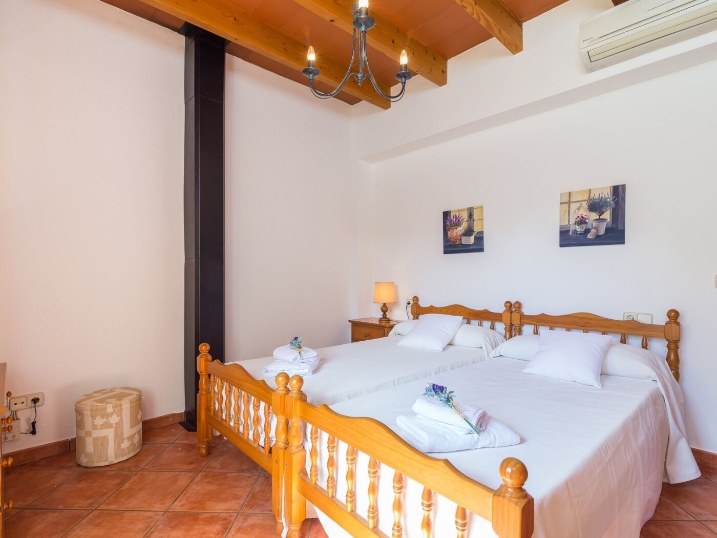 Una camera da letto con un letto di legno, lenzuola bianche, un lampadario e due quadri appesi al muro.