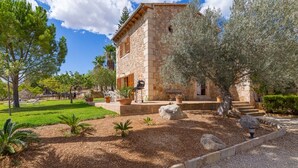 A stone building with a garden, outdoor seating, and a clear sky. - Banyols - Beautiful villa with pool in Alaró (Alaro)