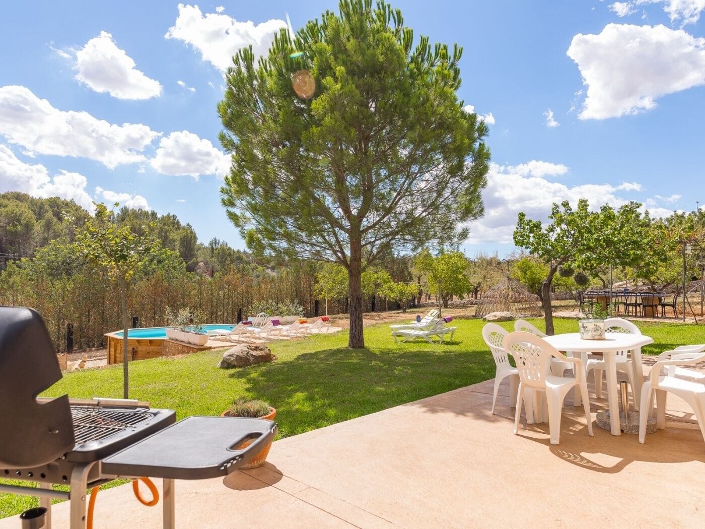 Une terrasse avec un barbecue, des meubles d’extérieur et une piscine.