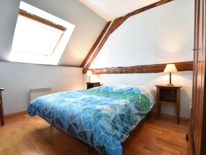 A bedroom with a sloped ceiling, a bed with a geometric-patterned bedspread, two bedside tables with lamps, and a window providing natural light. - Beautiful authentic holiday home with pool (Chantenay-Saint-Imbert)