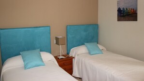 A room with two beds, each with a blue headboard, a nightstand with a lamp, and a painting on the wall. - 039 Villa Recuerdo (Denia)