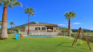 Una casa con piscina, tobogán y columpio.