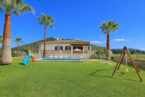 Une maison avec une piscine, un toboggan et une balançoire.