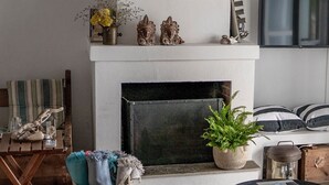 Una sala de estar con chimenea, un televisor montado en la pared y un rincón de descanso acogedor.