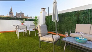 Una terrazza sul tetto con vista su un edificio storico, un muro verde e mobili da esterno.