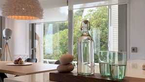 A modern kitchen with a large window, a hanging light fixture, and a bottle of water on the counter. - Holiday rental semidetached with swimming pool in Begur, Sa Tuna (Begur)