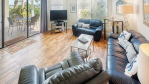 Un salon comprenant un canapé, un téléviseur et un coin repas avec des chaises.