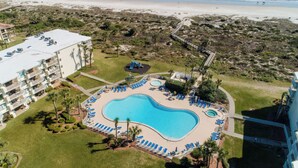 Vue aérienne d’un complexe hôtelier doté d’une grande piscine, d’un accès à la plage et d’une jetée.