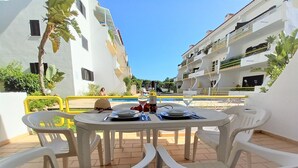 A table set for two with a bottle of wine and a glass of water, surrounded by white plastic chairs. - Sol Nascente- Pool, Cozy, Wifi, Calm area (Vilamoura)