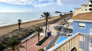 Une vue sur la plage avec une piscine, des palmiers et un bâtiment doté d’un toit en tuiles.