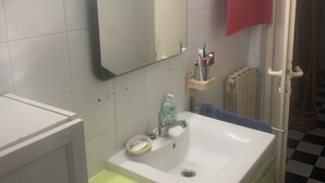 A bathroom with a white sink, a mirror with lights, a red towel, and a checkered floor.