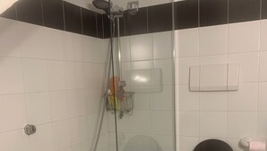 Ein Badezimmer mit einer Duschkabine, einer Toilette und einem Waschbecken.