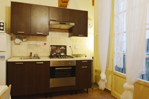 A kitchen with dark wooden cabinets, a stainless steel stove, and a clock on the wall.