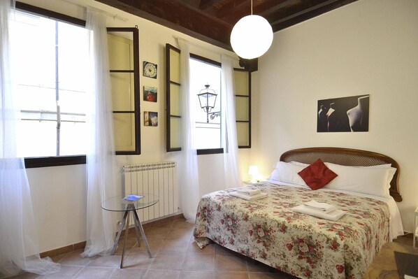 A bedroom with a bed, a small table, and a window with curtains.