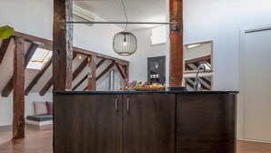 Un mueble de madera oscura con una superficie de cristal, una lámpara colgante y vistas a una escalera con vigas de madera.
