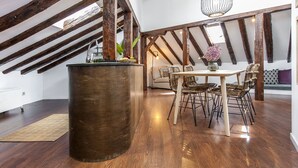 Un comedor rústico con una mesa redonda y sillas de mimbre, un barril de madera y vigas de madera a la vista.