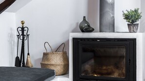 Una habitación acogedora con chimenea, una cesta de mimbre, una pequeña planta en maceta y una figura decorativa de metal.