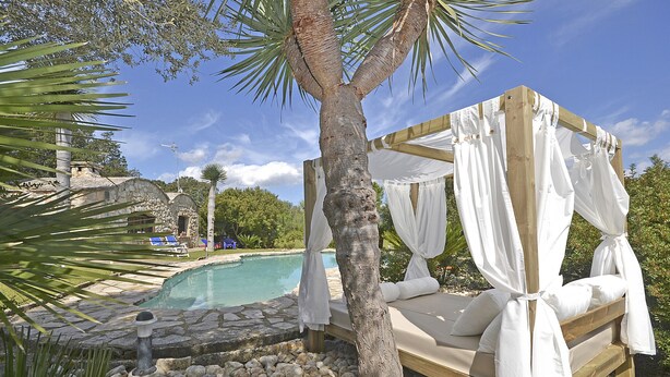A wooden bed with white canopy, a stone pool, and a palm tree. - Moli - Rural house with pool in Búger (Buger)