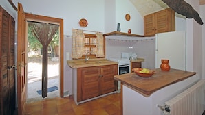 A kitchen with wooden cabinets, a sink, a stove, and a bowl of fruit on the counter. - Moli - Rural house with pool in Búger (Buger)