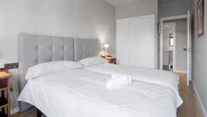 Un dormitorio con una cama grande, una mesita de noche con lámpara, un armario y una puerta que da a un baño.