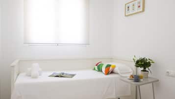 Cozy retreat with a single bed, a small table, and a potted plant.
