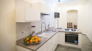 Une cuisine moderne dotée d’un four encastré, d’un évier et d’un plan de travail sur lequel se trouve un panier de fruits.