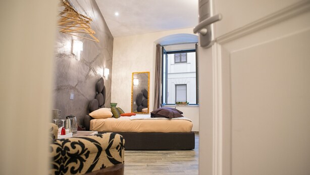 Une chambre à coucher avec un lit, un miroir, une fenêtre et une porte.