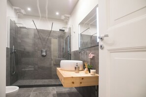 Et moderne badeværelse med et glasafskærmet brusebad, et trækommode med vask og et spejl.