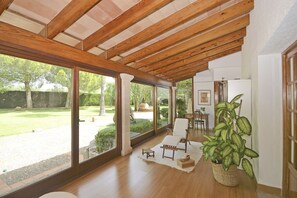 A spacious room with large windows, wooden beams, a dining area, and a potted plant. - Bennassar - Beautiful country house with pool in Inca, Mallorca (Inca)