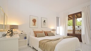 Um quarto com uma cama, mesas de cabeceira, uma bicicleta e obras de arte na parede.