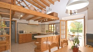 Uma cozinha com armários de madeira, uma ilha central e uma área de jantar com mesa e cadeiras.