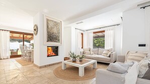 Ein Wohnzimmer mit Kamin, einer Couch, einem Couchtisch und einem Essbereich mit Stühlen.