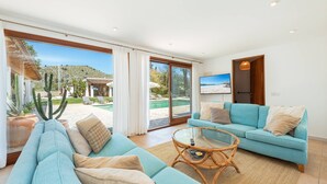 Ein Wohnzimmer mit einer Couch, einem Glastisch und einem Fernseher.
