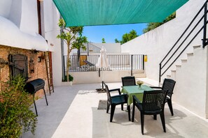 Une terrasse avec une table et des chaises, un barbecue et un escalier.