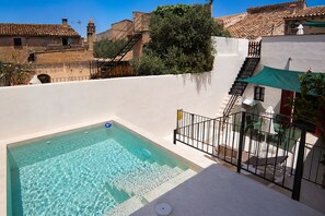 Une piscine à l’eau claire, un escalier et une terrasse aménagée avec du mobilier d’extérieur.