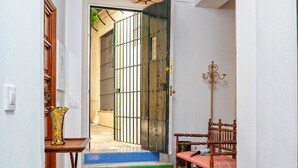 Un couloir avec une arche blanche, un banc en bois, une table avec un vase et un luminaire suspendu.