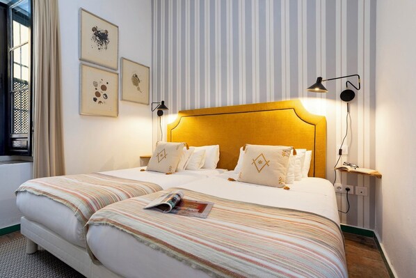 A neatly made bed with striped bedding, a headboard, and two bedside lamps.