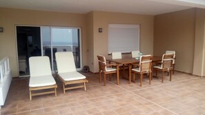 Ein Balkon mit Esstisch und Stühlen, einer Schiebetür aus Glas und einer weißen Wand.