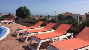 A poolside area with sun loungers and a swimming pool.