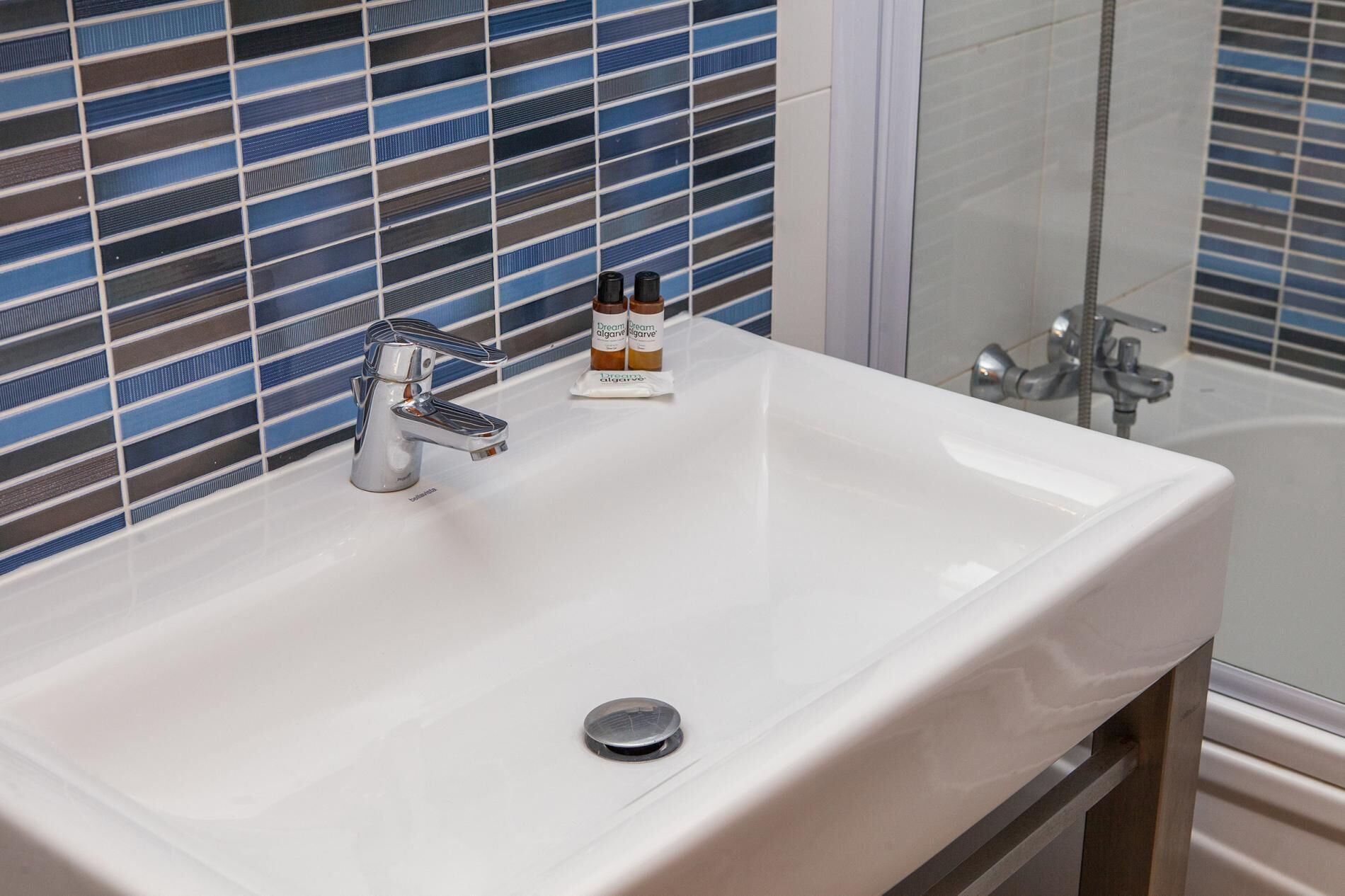 A bathroom with a white sink, a modern faucet, and a glass shower enclosure.