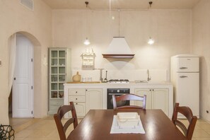 Een koelkast, een oven, een kookplaat, kookgerei, borden en bestek