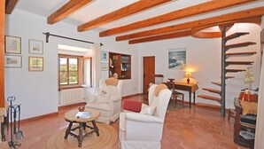 Una sala de estar espaciosa con muebles blancos, techo de madera y una escalera en espiral.