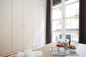 A hotel room with a large window, a breakfast tray with coffee, tea, and pastries, and a view of the outside balcony. - Singular Stays Botanico 102 (Valencia ciudad)
